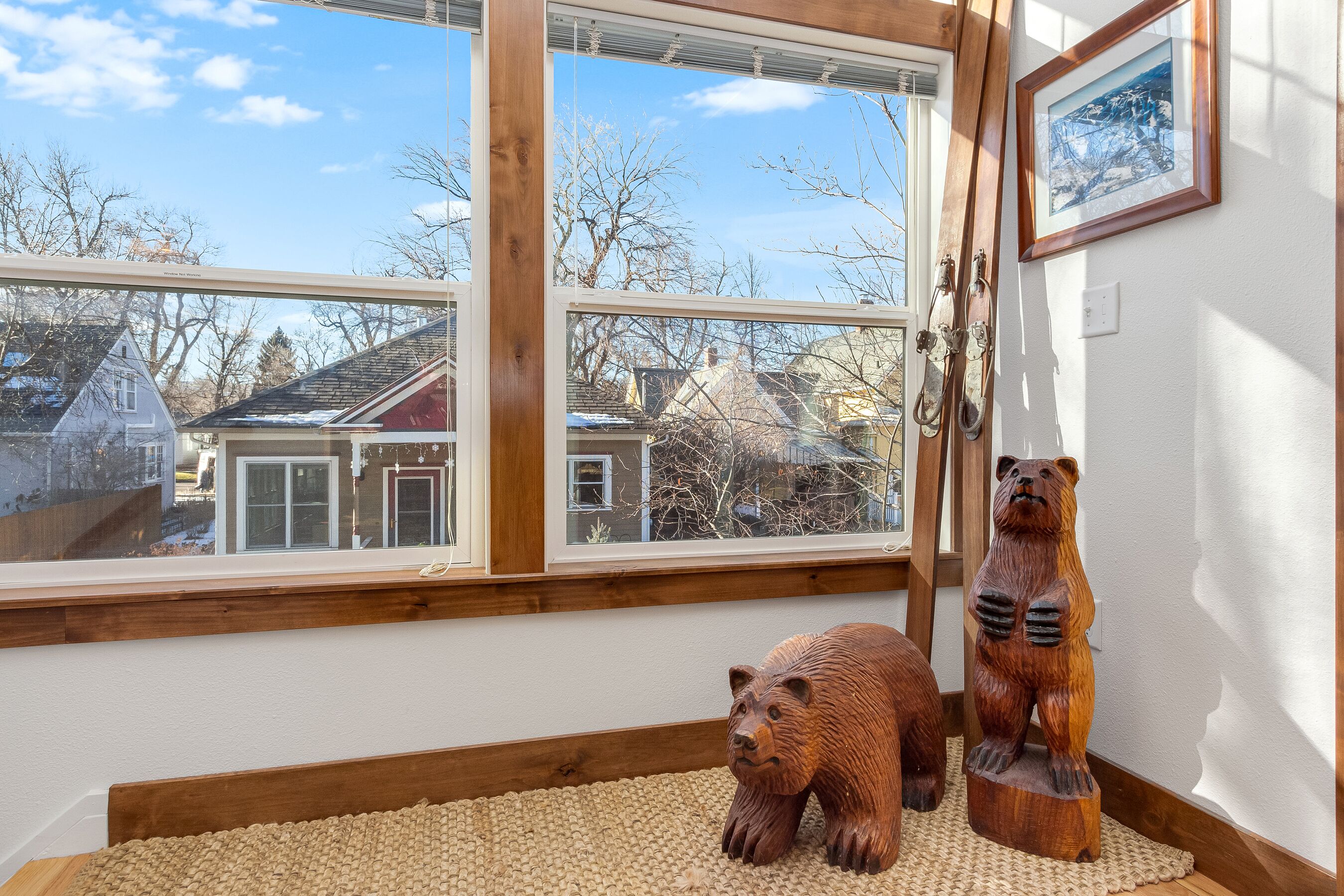 Une pièce dotée d’une grande fenêtre, d’une sculpture d’ours en bois et d’un tableau encadré accroché au mur.