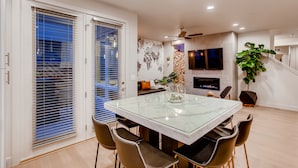 Un espace repas avec une table et des chaises en verre, une cheminée et un escalier.