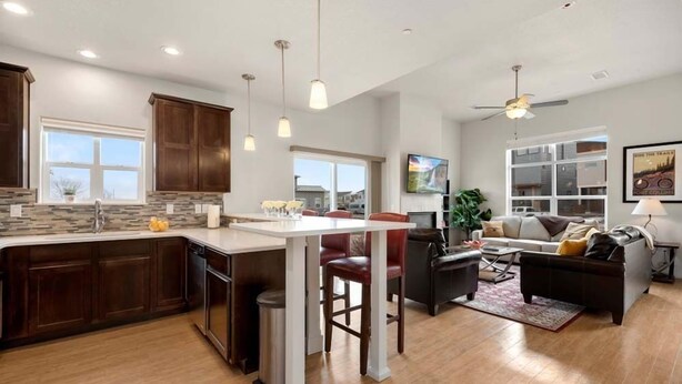 A modern kitchen with a central island, wooden cabinets, and pendant lighting.