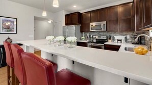 A modern kitchen with dark wood cabinets, stainless steel appliances, and a white island with bar stools.