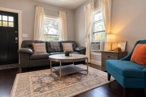 A living room with a sofa, a blue armchair, a coffee table, and a rug.