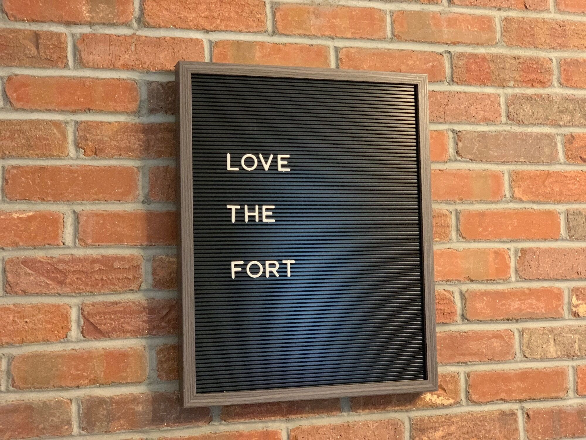 A sign with the words "LOVE THE FORT" mounted on a brick wall.