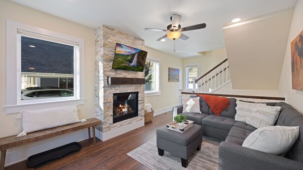 A living room with a stone fireplace, a ceiling fan, and a gray sectional sofa. - Cozy Home in Downtown Loveland W/ Free Bikes! (Loveland)