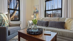 A living room with a sofa, armchair, coffee table, and a vase with greenery. - Cozy Home in Downtown Loveland W/ Free Bikes! (Loveland)