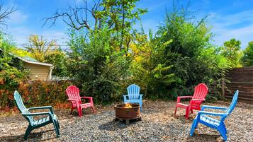 Patio trasero con un brasero rodeado de sillas Adirondack.