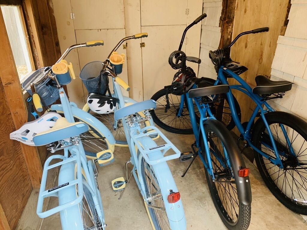 Een garage met drie fietsen, waarvan één blauw en twee lichtblauw, met diverse accessoires.