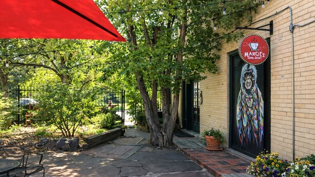 A brick building with a mural, outdoor seating, and a red umbrella. - Inviting Bungalow Next to Unc - Free Cruiser Bikes! (Greeley)