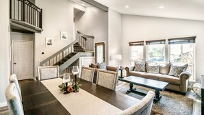 Un salon spacieux comprenant un coin repas, un escalier et de grandes fenêtres.