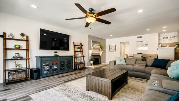 Un salon moderne doté d’un téléviseur à écran plat, d’un ventilateur de plafond, d’une cheminée, d’un canapé et d’une table basse.