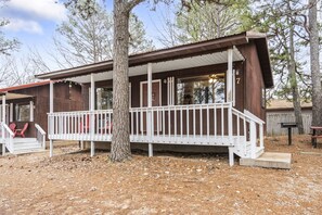 A wooden cabin with a porch, two red chairs, and a number '7' sign.