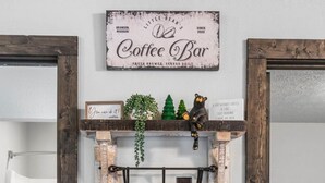 A coffee bar with a rustic wooden design, a coffee machine, mugs, and a sign reading "Coffee Bar". - Charming Rustic Retreat - Hot Tub - Pool - Coffee - Fire Pit - 1 mile from SDC! (Branson)