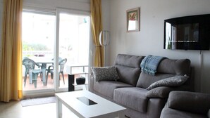 A living room with a grey sofa, a white coffee table, and a TV mounted on the wall.