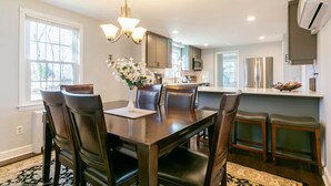 A modern kitchen with dark wood cabinetry, a central island, and a dining area with a dark wood table and chairs.