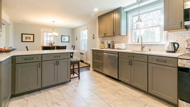 A modern kitchen with grey cabinets, a central island, and a dishwasher.