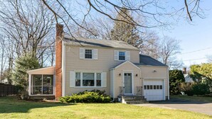 A two-story house with a front porch, a garage, and a covered patio area.