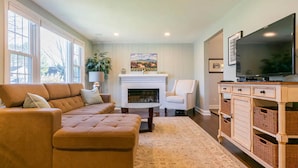 A living room with a sectional sofa, a fireplace, a television, and wicker baskets.