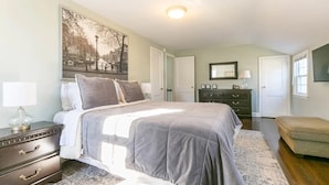 A bedroom with a bed, dresser, nightstand, and a large framed picture on the wall.