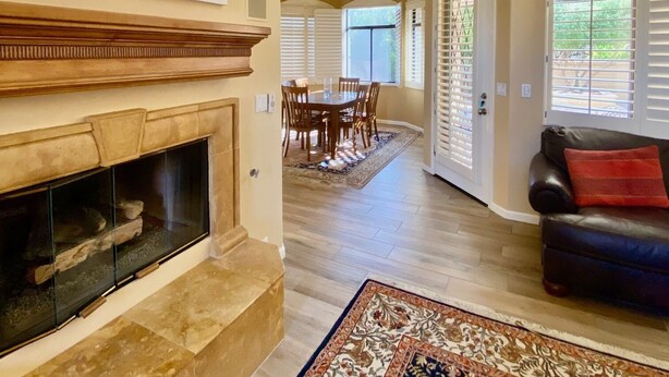 A spacious living room with a fireplace, a dining area with a table and chairs, and a cozy seating area with a leather couch.