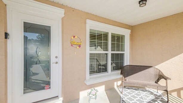 A house entrance with a glass door, a welcome sign, a wicker chair, and a patterned rug. - Trailside Oasis: 3BR Pool & Spa – Minutes from Trail, Ocala & Crystal River (Inverness)
