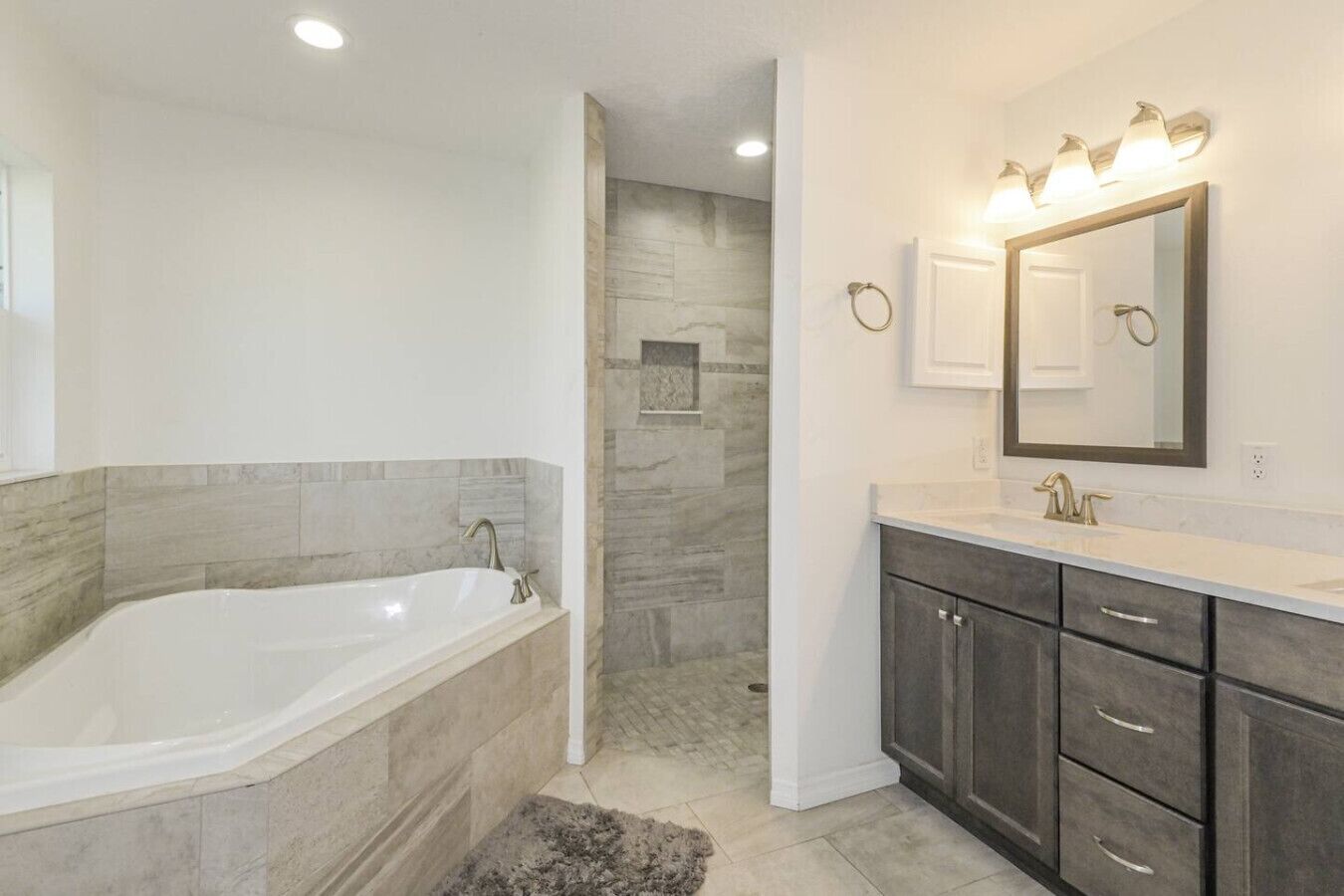 A modern bathroom with a freestanding bathtub, a vanity with a mirror, and a shower area.