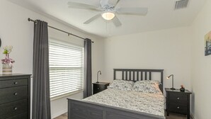 A bedroom with a bed, bedside tables, a ceiling fan, and a window with curtains. - Trailside Oasis: 3BR Pool & Spa – Minutes from Trail, Ocala & Crystal River (Inverness)
