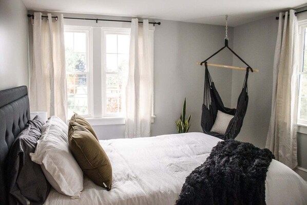 A bedroom with a bed, pillows, a hanging chair, and a window with curtains. - ❤Beautifully Renovated Lancaster Apt❤ (Lancaster)