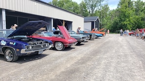 A row of vintage cars parked in front of a building with open garage doors. - Calabogie Motor Inn (Greater Madawaska)