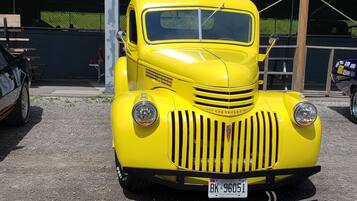 A yellow vintage Chevrolet car parked in front of a building.