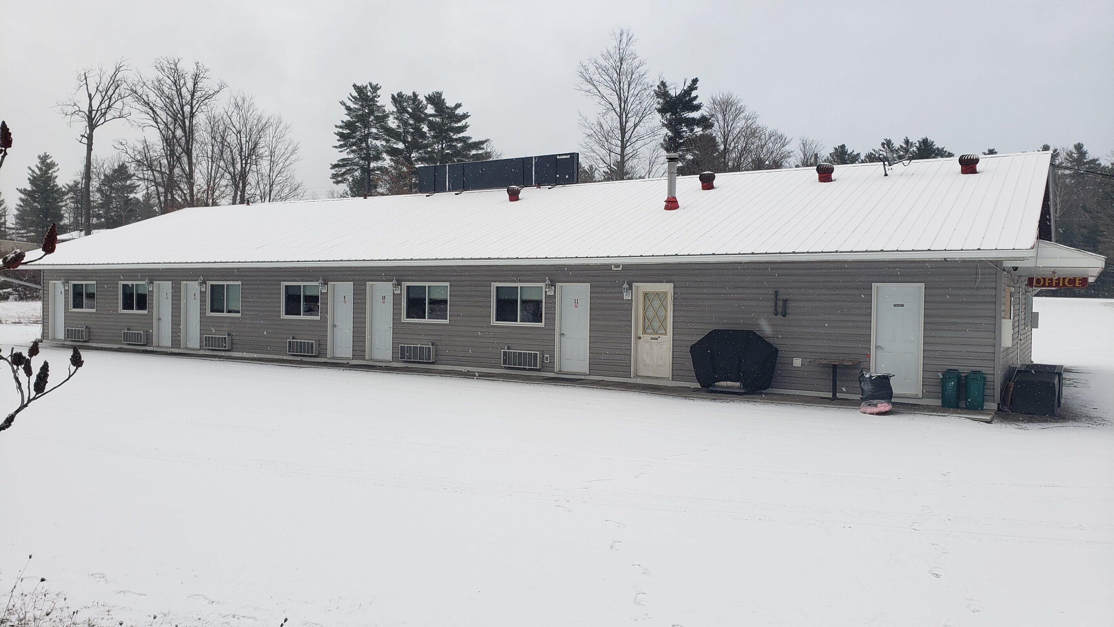 A single-story building with a snow-covered roof and a small office annex.