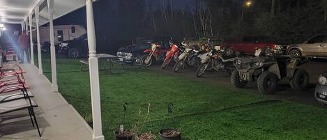 Un espacio exterior cubierto con césped artificial, plantas en macetas y varias motocicletas y cuatrimotos estacionadas.