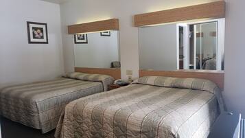 Een hotelkamer met twee eenpersoonsbedden, een nachtkastje met een telefoon en een spiegel die de kamer weerkaatst.