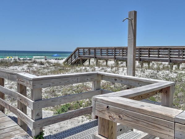 A wooden boardwalk leading to a beach with umbrellas and a wooden structure.