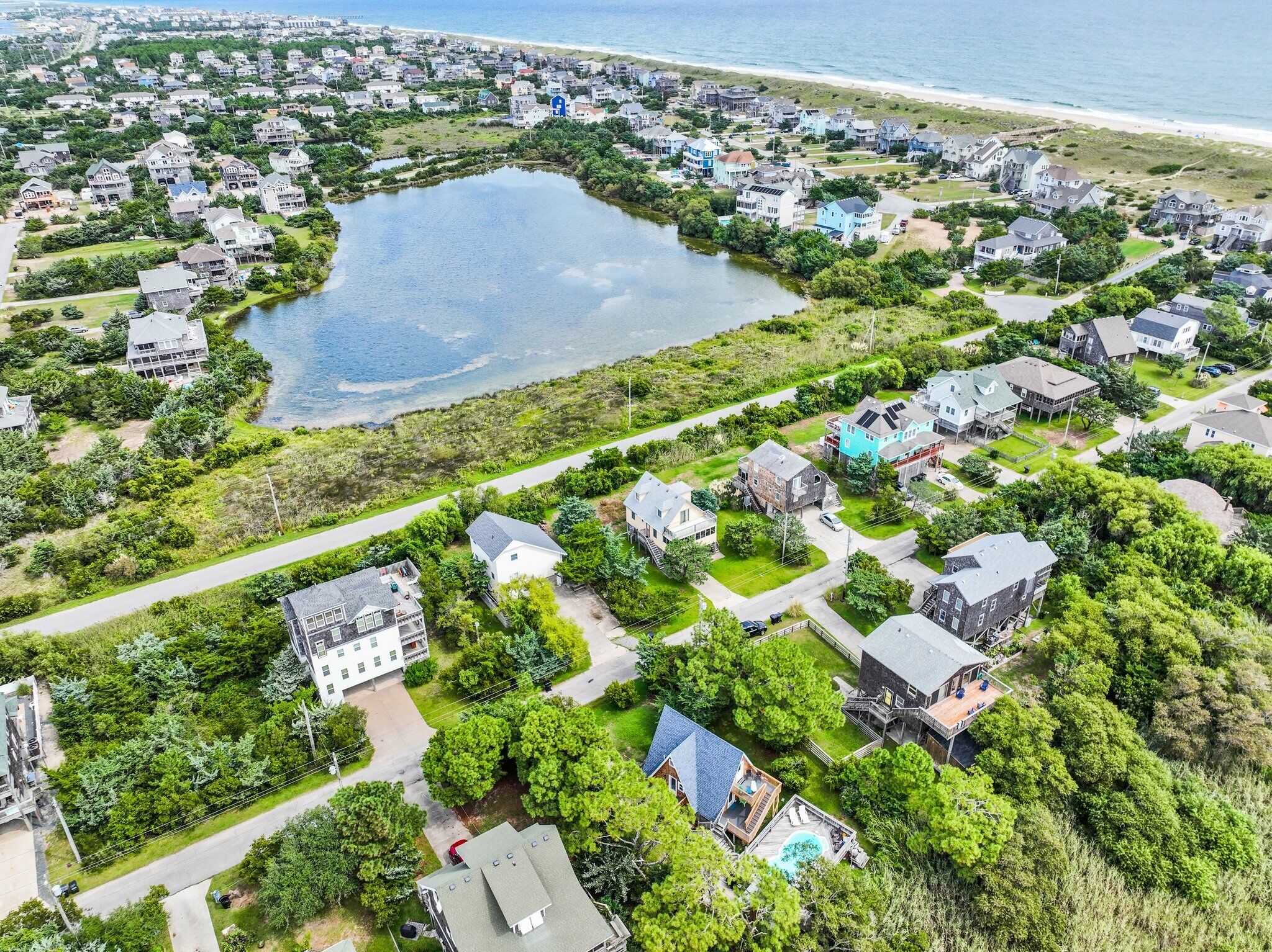 An aerial view of a coastal residential area with houses, a lake, and a beach.