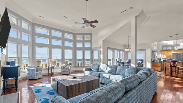 A spacious living room with a large sofa, a coffee table, and a view of the ocean. - Soundfront, Pool, Hot Tub, Elevator, Private Dock, Boat Ramp, & Game Room (Salvo)