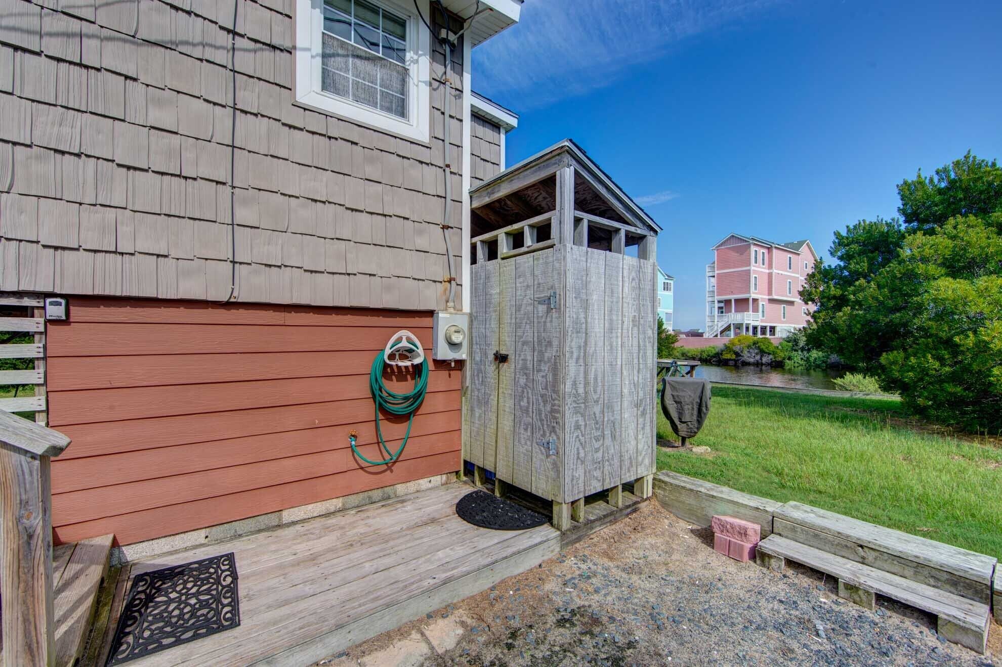 A wooden shed with a door, a hose, and a small step leading to a porch.