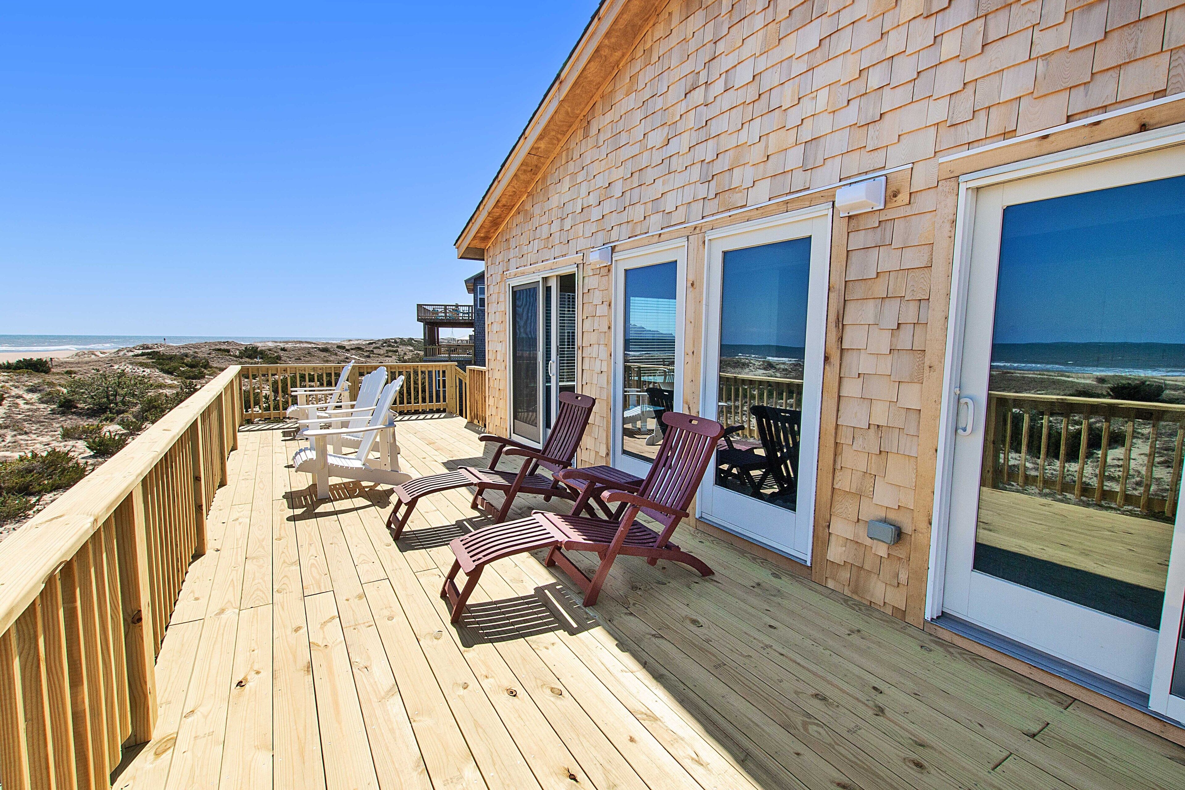 Une terrasse en bois avec des sièges extérieurs et une vue sur la plage.