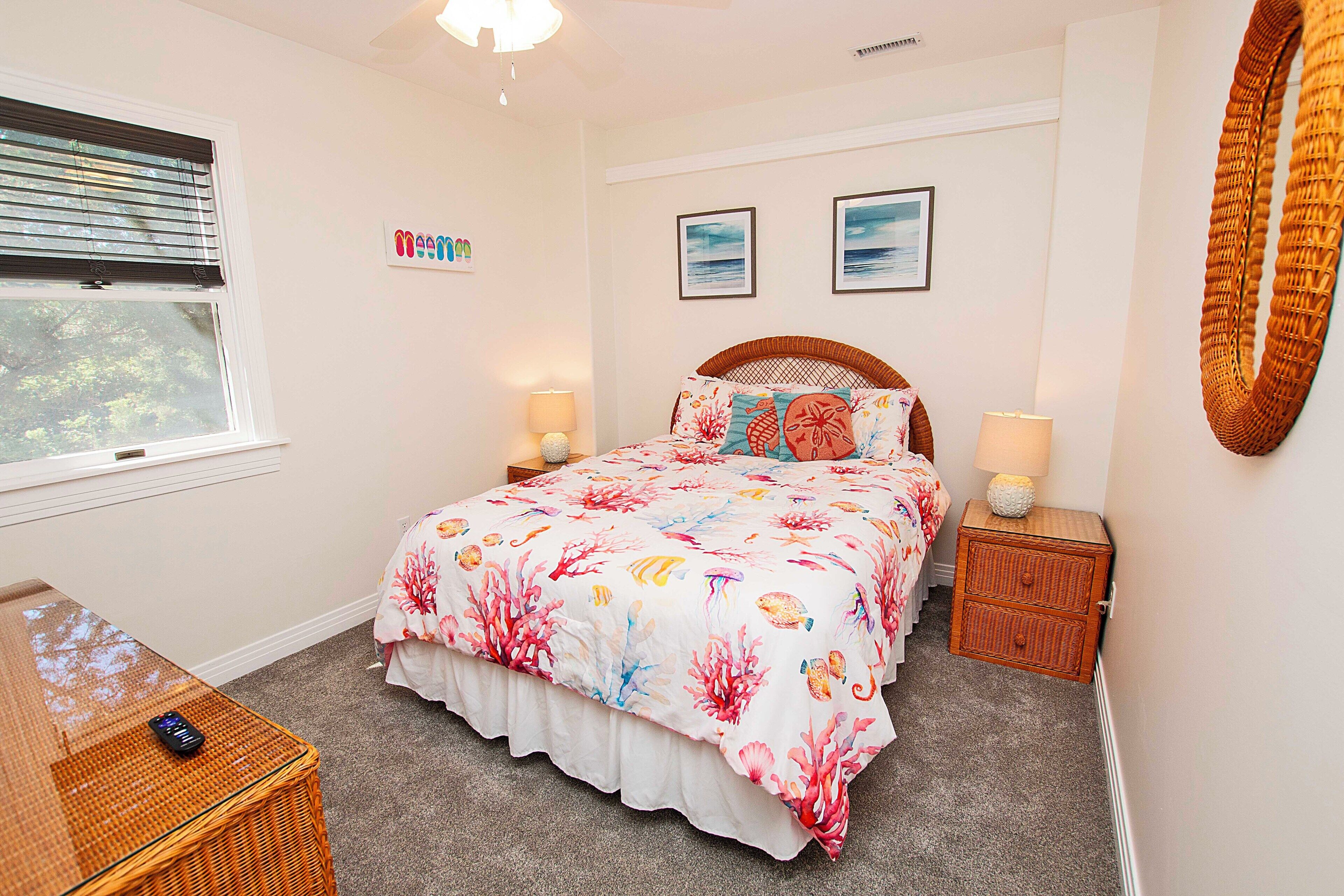 Une chambre à coucher comprenant un lit, deux tables de chevet, une commode, une fenêtre avec stores et une lampe fixée au mur.