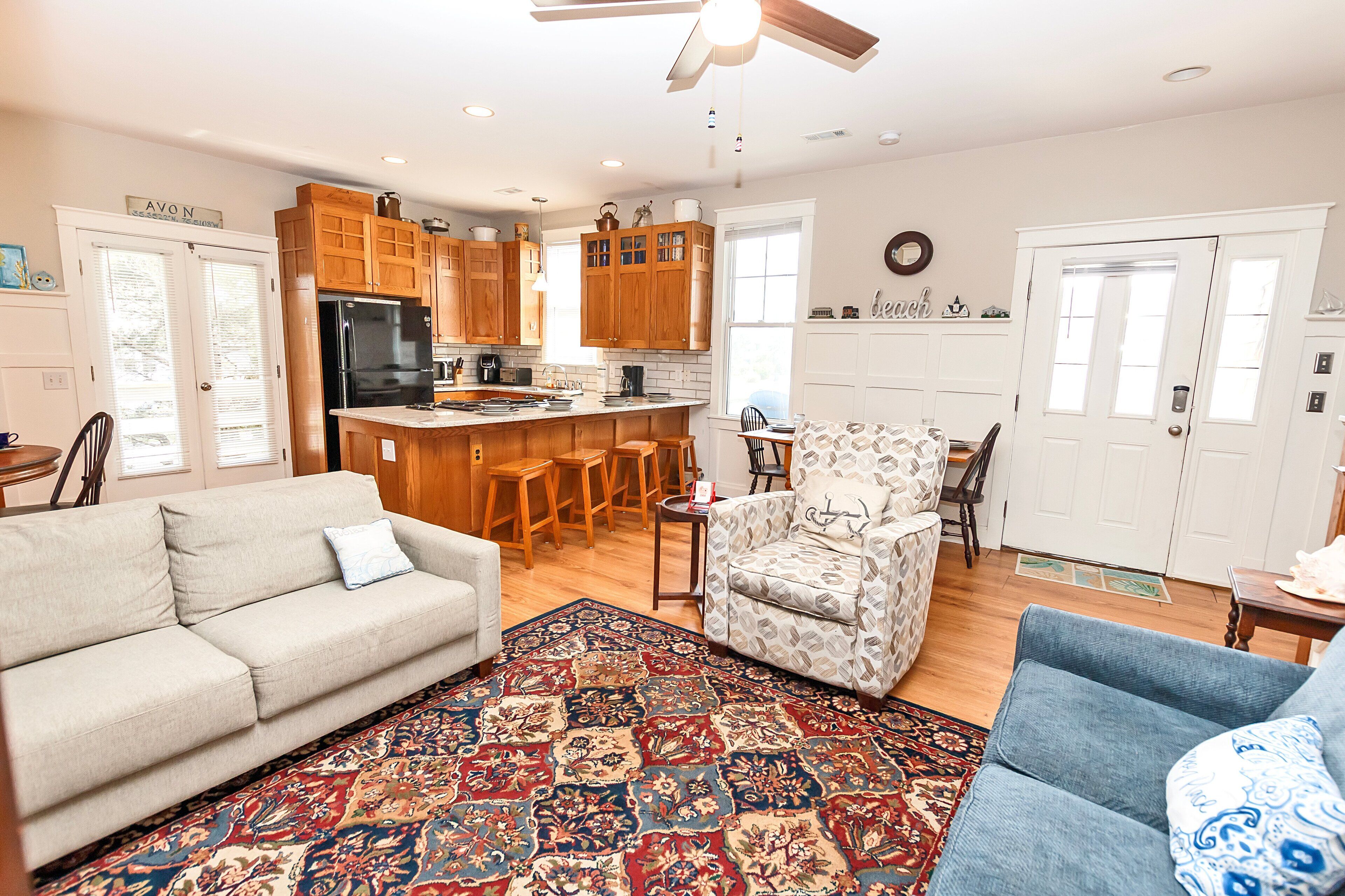 A spacious living room with a large rug, a sofa, a patterned armchair, and a blue armchair.