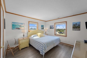 A bedroom with a bed, bedside tables, a chair, and artwork on the walls.