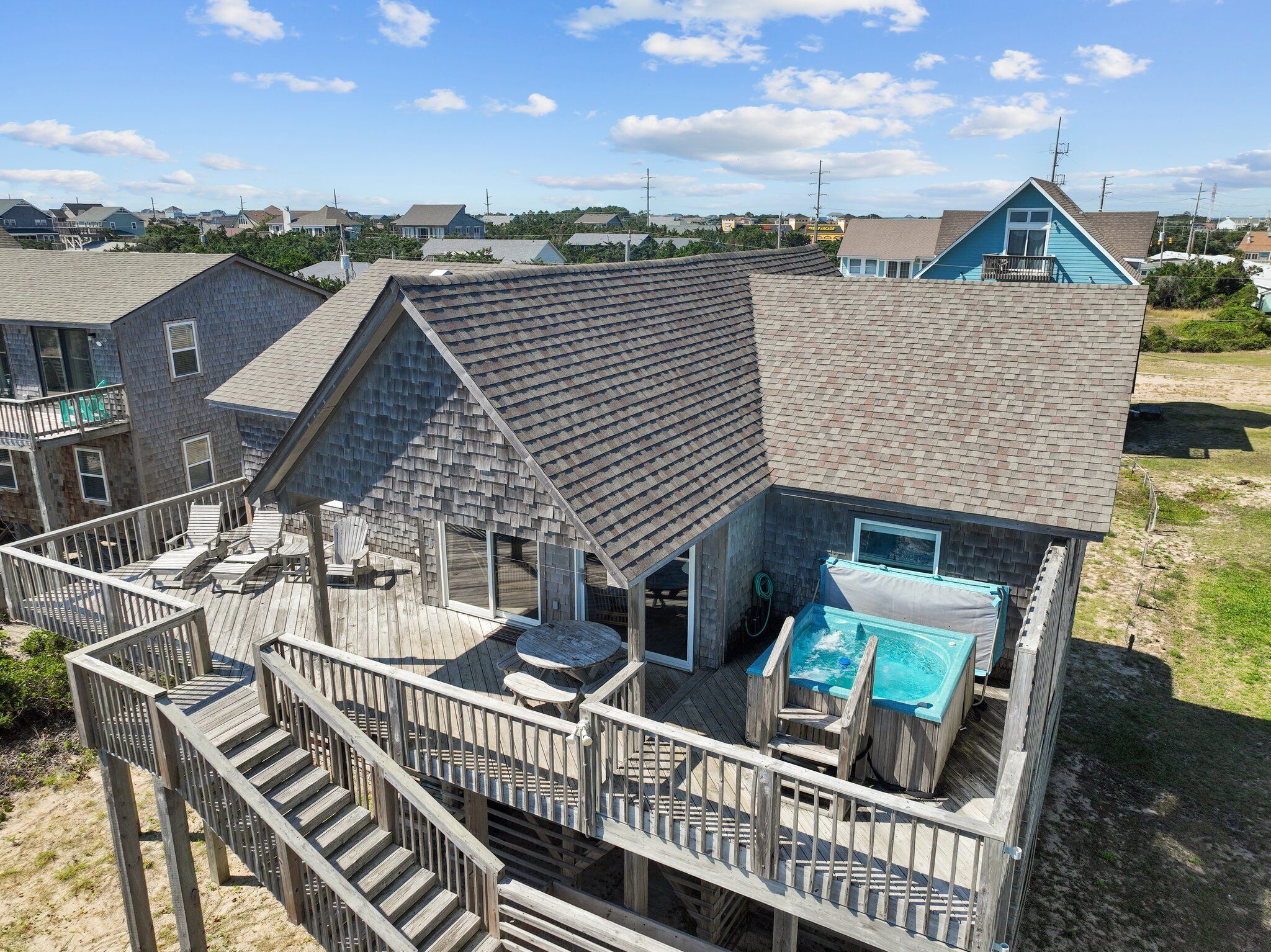 Une maison située en bord de mer, dotée d’une terrasse en bois, d’un jacuzzi et d’une piscine.