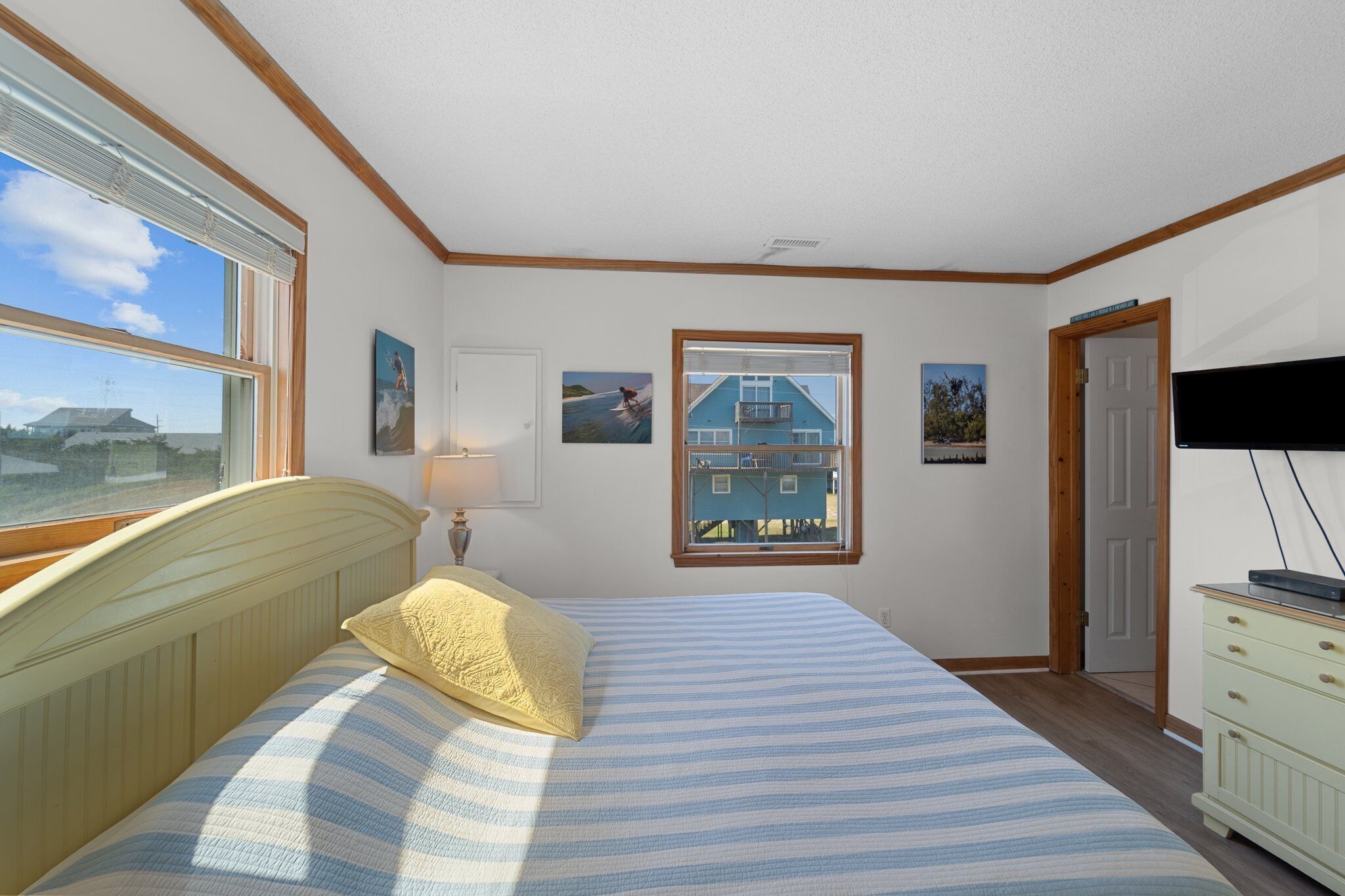 A bedroom with a bed, a window, a door, and a television.