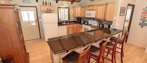 Una cocina con armarios de madera, encimera de granito y estufa integrada.