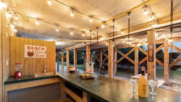 A beach bar with wooden beams, a bar counter, and a sign indicating it offers cool drinks and water wings. - Dogs Welcome, 25 Yards to Beach Access, Private Pool & Hot Tub (Avon)