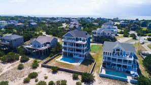 A coastal residential area with multiple two-story houses featuring balconies and a central swimming pool. - Oceanfront, Private Pool, Hot Tub, Theatre, Game Room, & Dog Friendly (Salvo)