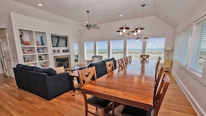 A spacious living area with a large wooden dining table, a sofa, and a fireplace. - Oceanfront, Private Pool, Hot Tub, Theatre, Game Room, & Dog Friendly (Salvo)