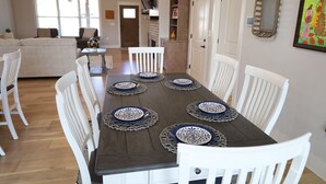 A dining area with a wooden table set for six, surrounded by white chairs. - Modern Family-sized Country Gem near Chattanooga with relaxing balcony & deck! (Ringgold)