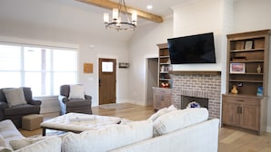 A spacious living room with a fireplace, a flat-screen TV mounted above it, and a comfortable seating area with sofas and a coffee table. - Modern Family-sized Country Gem near Chattanooga with relaxing balcony & deck! (Ringgold)