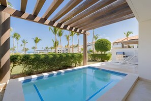Relax by the serene pool surrounded by lush greenery and a stylish pergola.