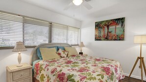A bedroom with a bed, a nightstand, a lamp, a painting, and a ceiling fan. - Vibrant 1bed/1bath Golf Course Front in the Meadows (Sarasota)