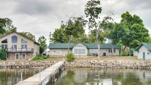 Una propiedad junto al lago con muelle, muros de piedra y varias casas con techos verdes.